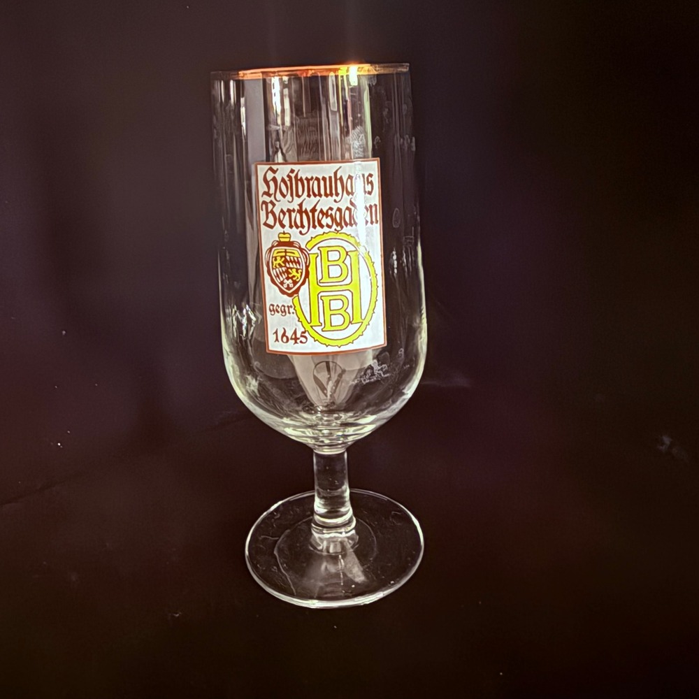 A Hofbrauhaus Berchtesgaden beer glass with a gold rim and founding date.